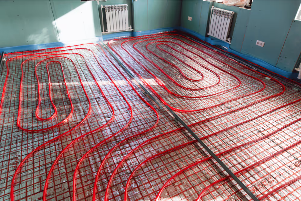 Underfloor heating system installation with red heating pipes arranged on a reinforced grid in a residential home.