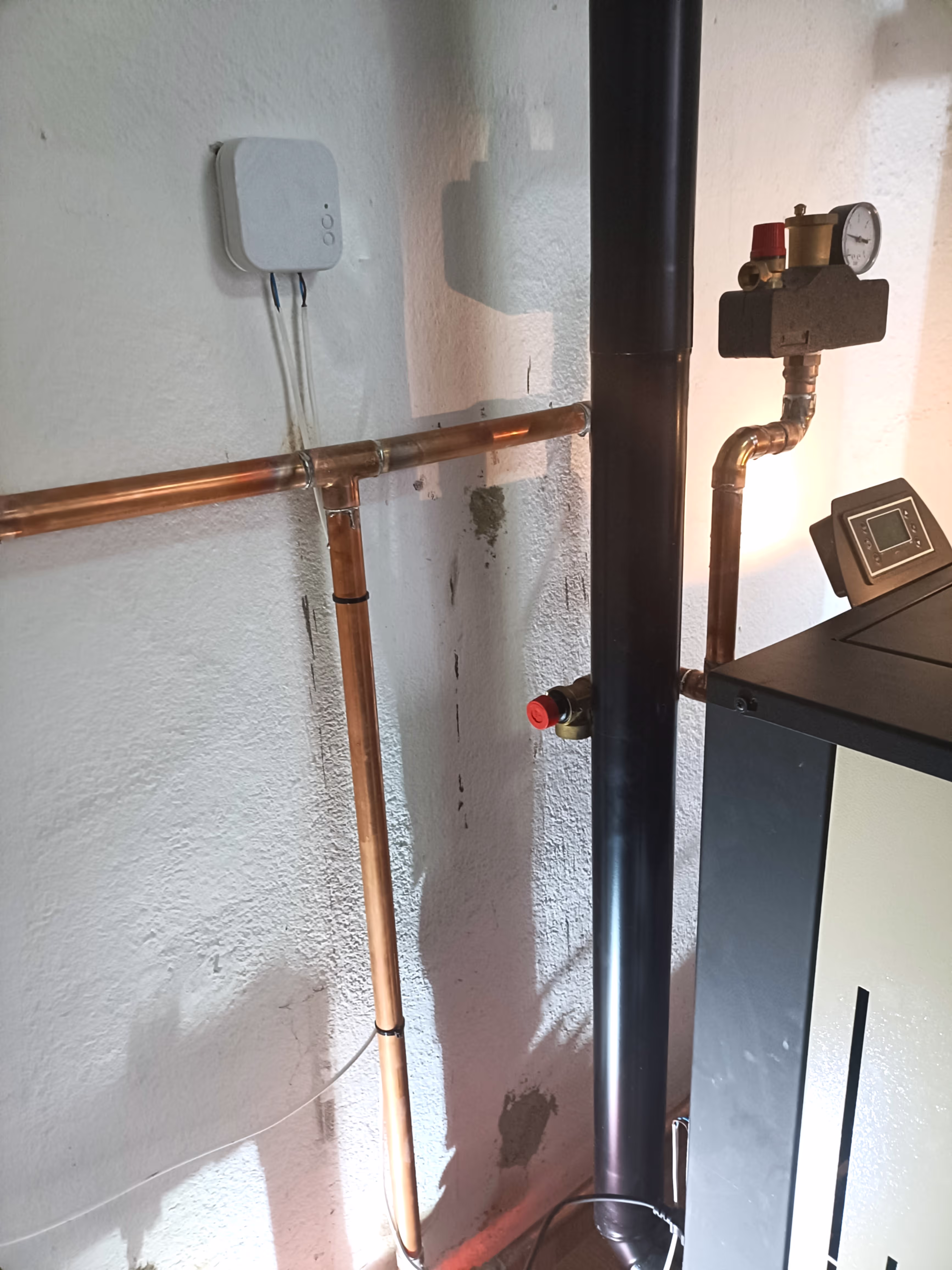 A close-up view of a black exhaust pipe connected to the heating system and extending to the wall.