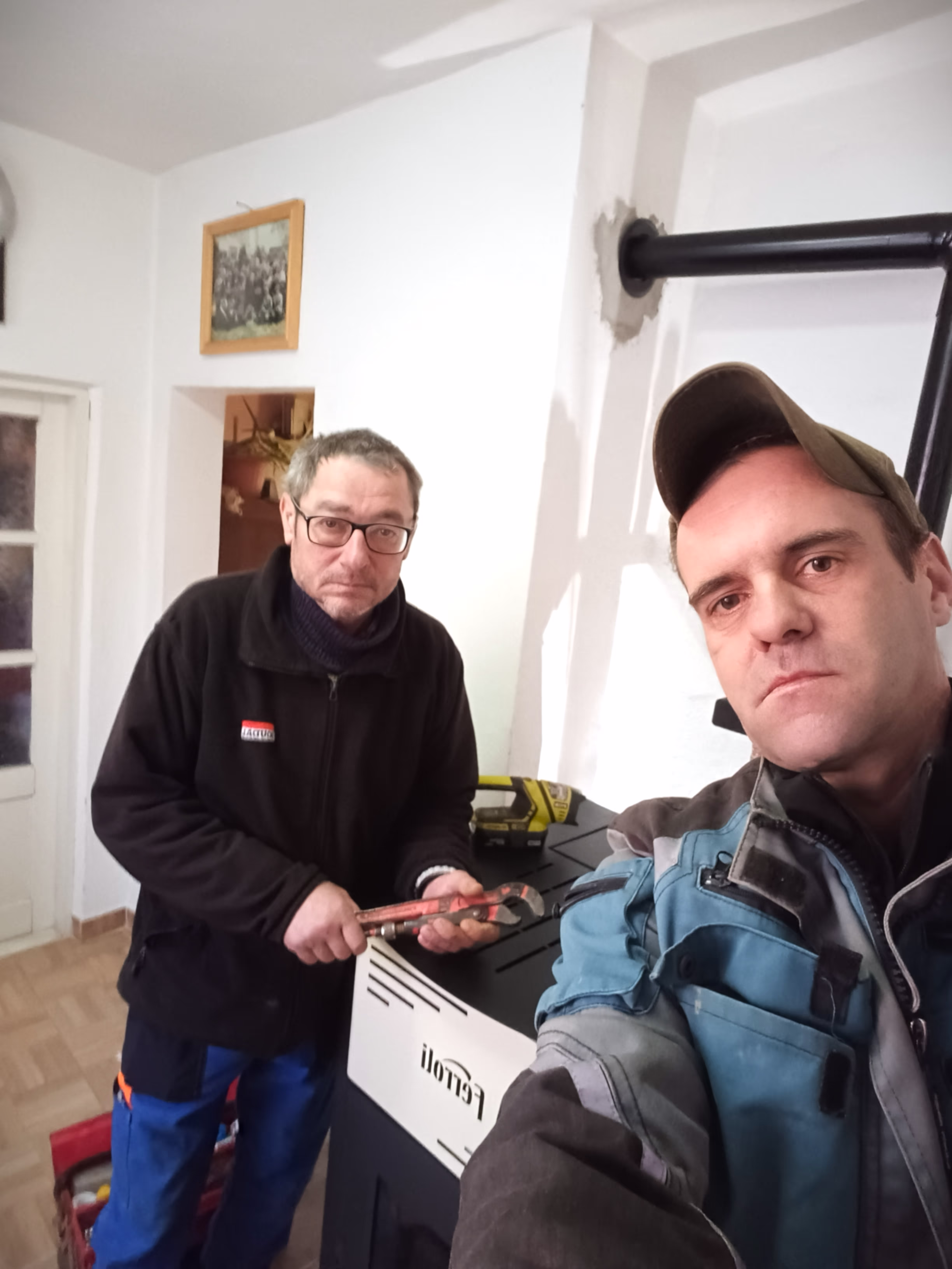Two workers posing for a selfie after installing a Ferroli heating stove.